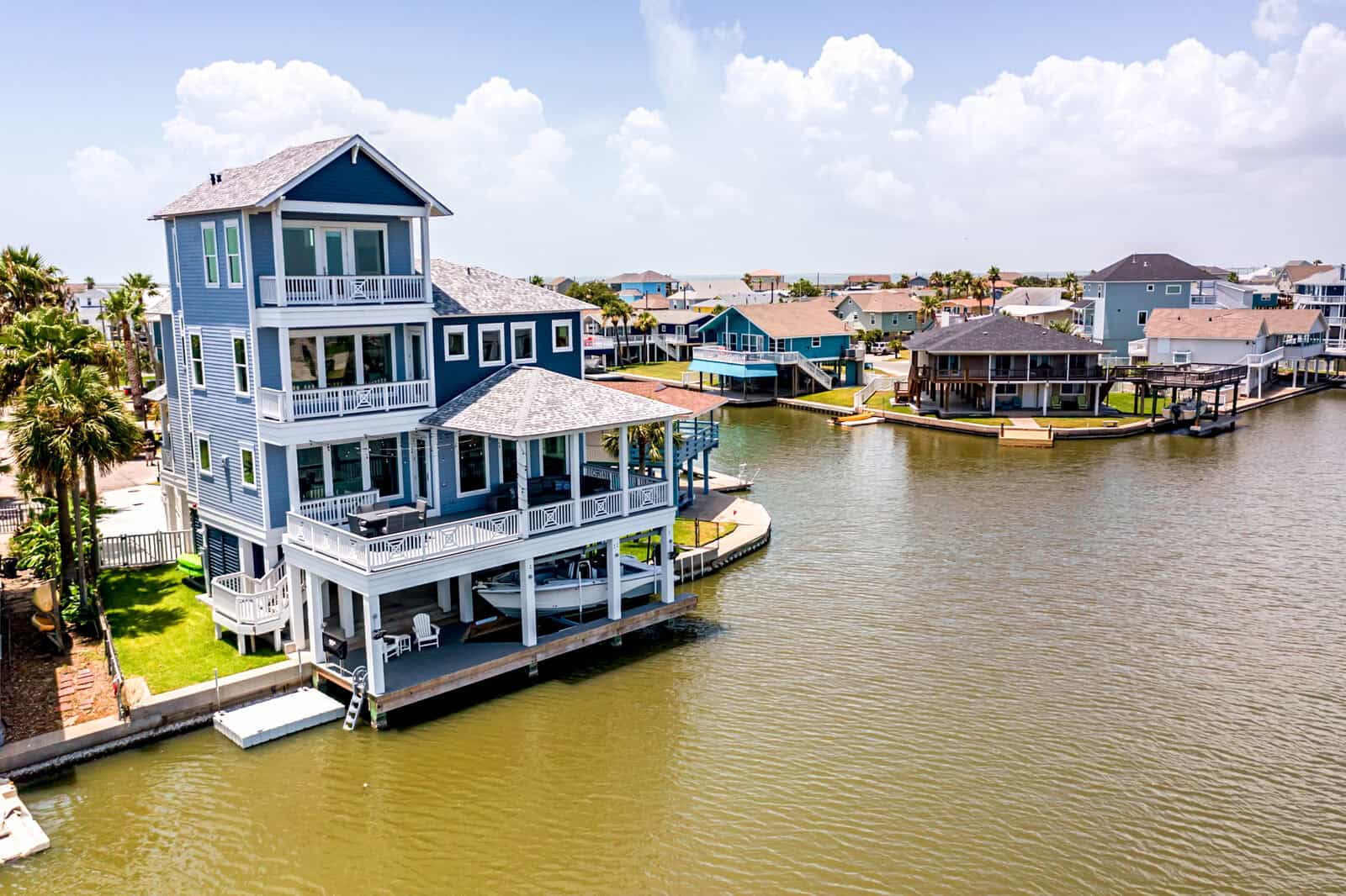 Elevated waterfront home on a canal with a boat stored in the open ground level beneath the house, allowing floodwater to pass through