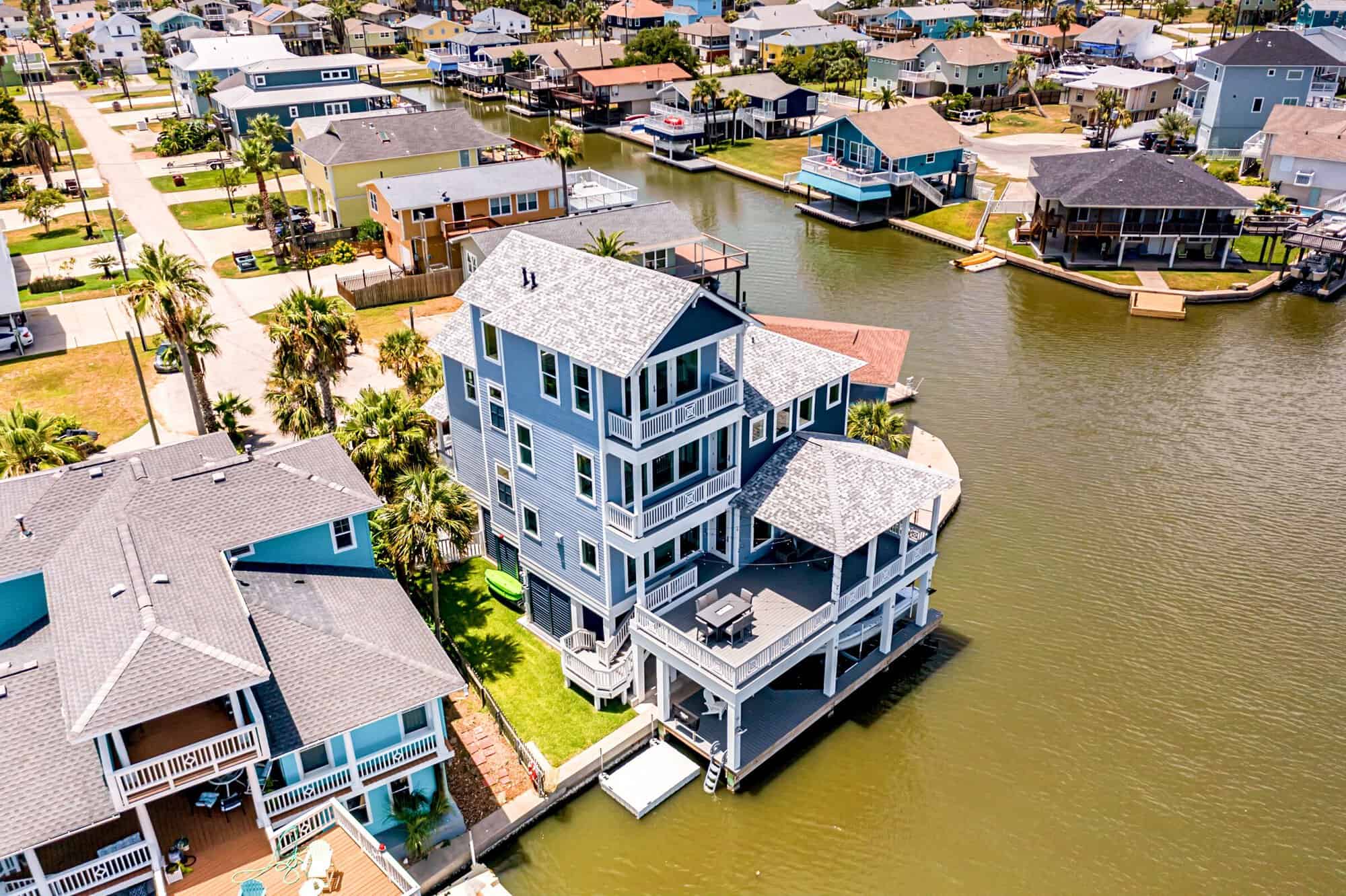 Aerial view of multi-level covered decks and a boat dock on a canal at a Kai Custom Homes build in Jamaica Beach, Texas