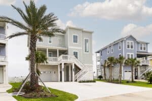 Homepage Elevated beach home with a date palm, driveway and double entry stairs, built by Kai Custom Homes in Pointe West, Galveston