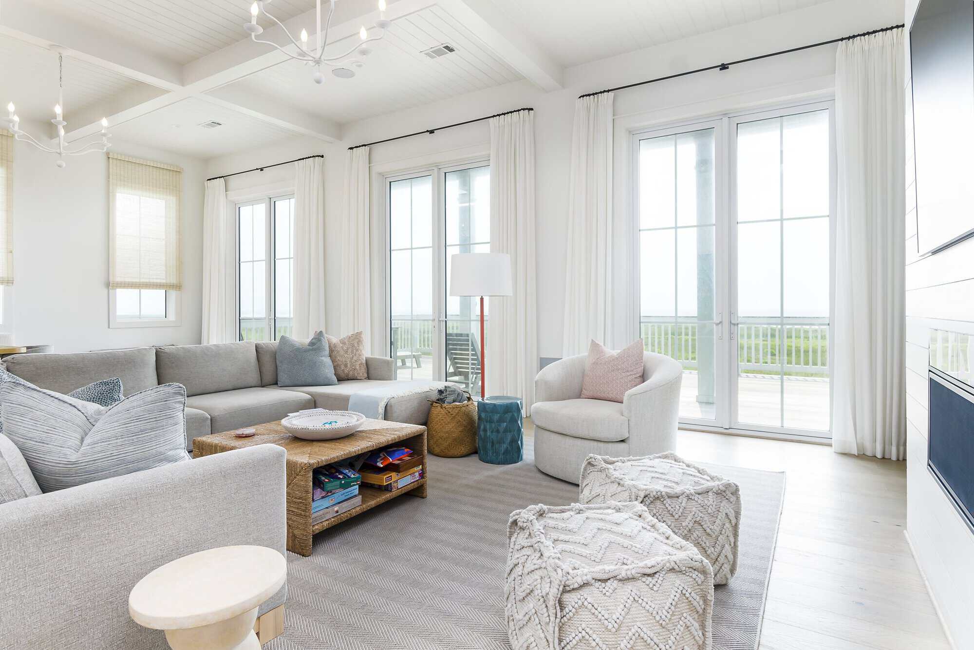 Living room with a coffered shiplap ceiling and sliding doors to an ocean-view deck in a Kai Custom Homes build in Pointe West, Galveston